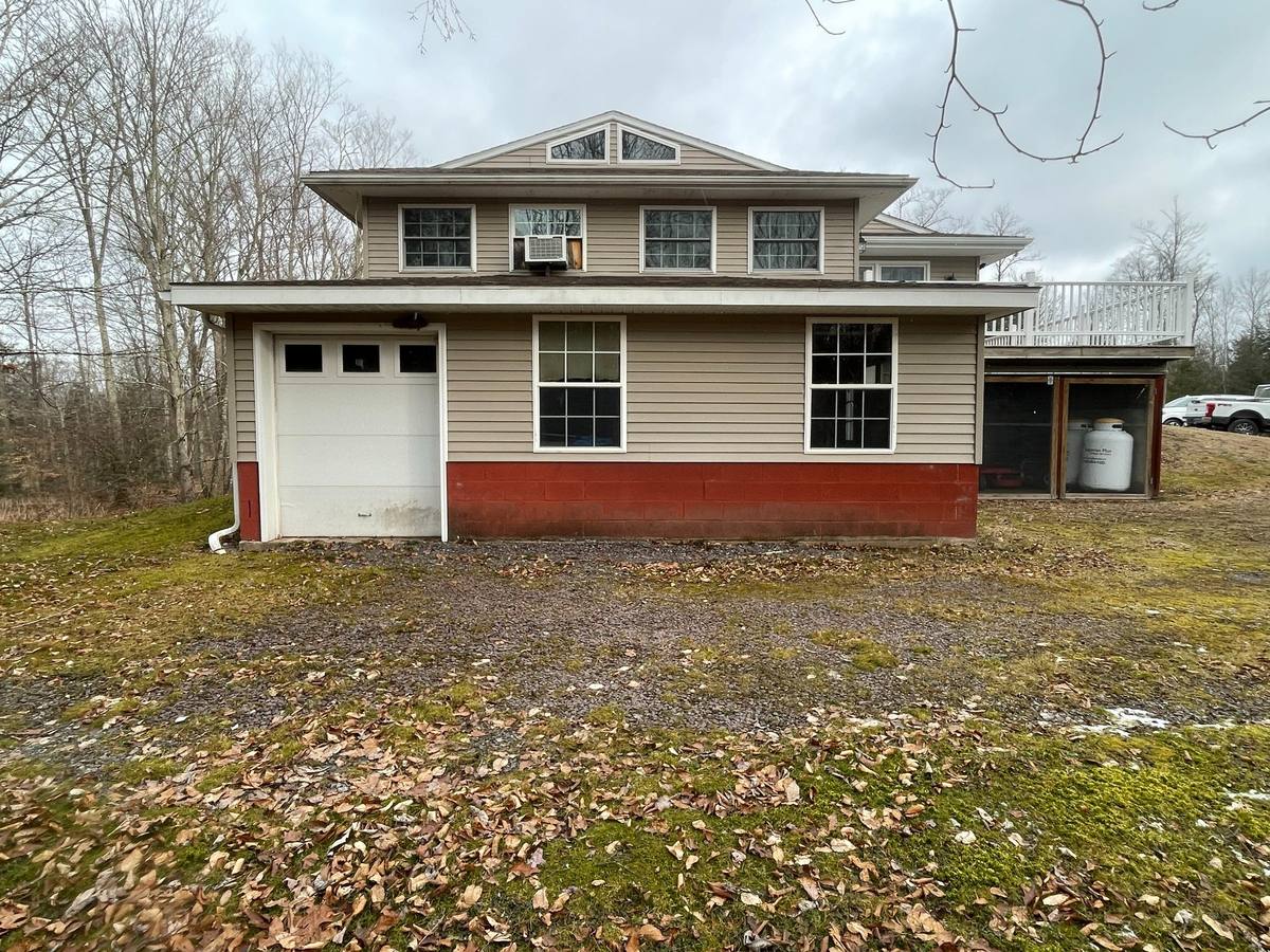 Existing rear side of the Residence showing the original structure, garage, and deck condition